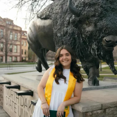 graduate in front of bison statue