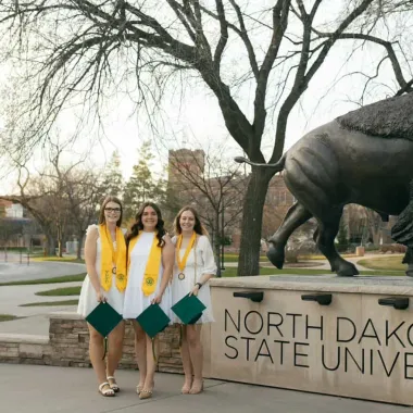 group of graduates in front of the bison statue