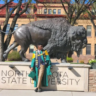 graduate in front of bison statue