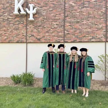 group of graduates in front of greek life house