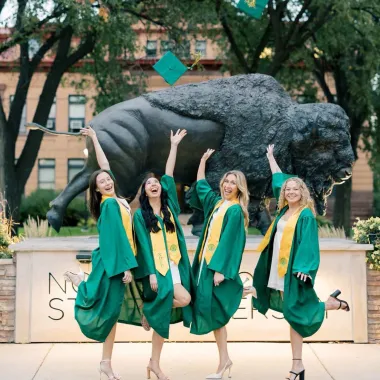 group of graduates in front of the bison statue