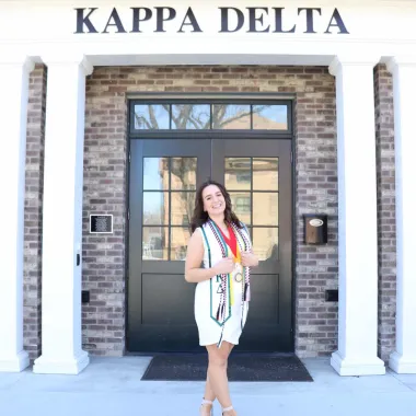 graduate in front of her greek life house