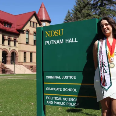 graduate in front of Putnam Hall
