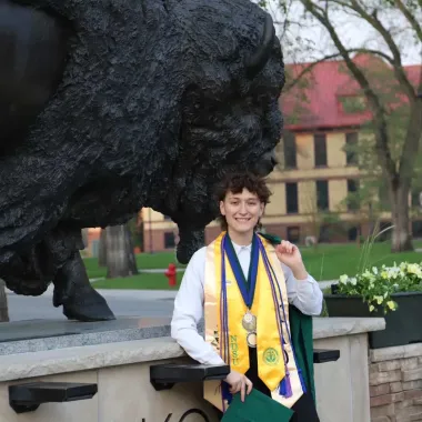 graduate in front of bison statue