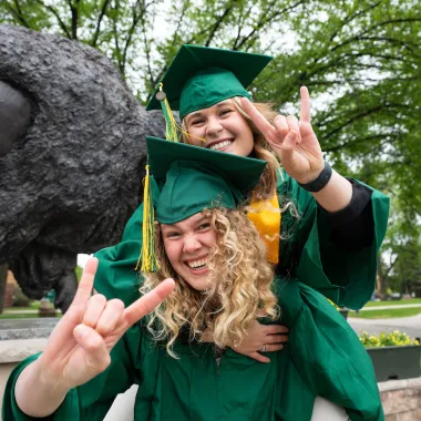 graduates in front of the bison statue