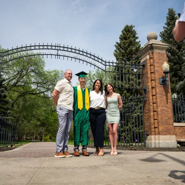 graduate and family in front of NDSU gates