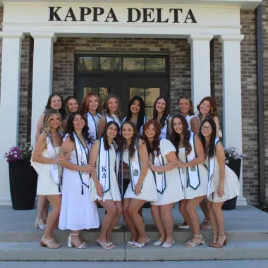 group of students posing in front of their sorority house
