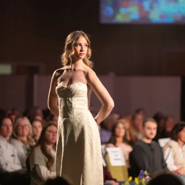 Model wearing a floor-length off-white dress.