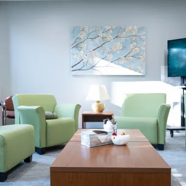 Group room in Counseling Center with green comfy chairs and media station.