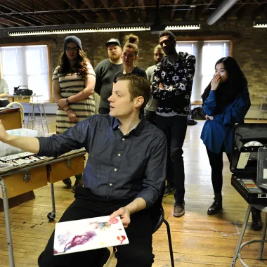 Faculty teaching while painting in painting studio.