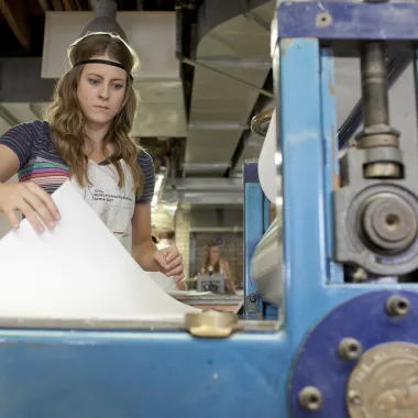 Student working with printmaking equipment in the printmaking studio.