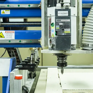 Machine cutting wood located in woodshop.