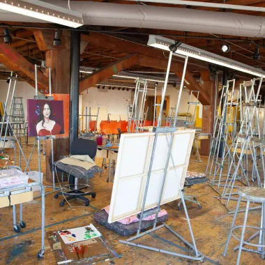 Easels, stools and artwork in painting studio.