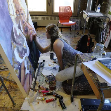 Student working with paint on canvas in painting studio.