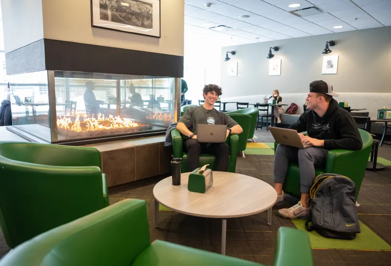 two students lounging next to a fire in a dining center
