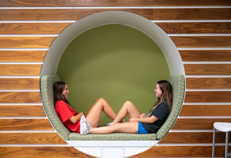 Two students lounging in a circular cubby in Cater Hall