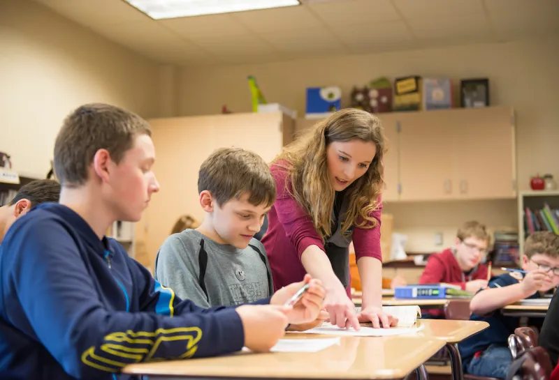 Education student helping young students in the classroom as part of student teaching
