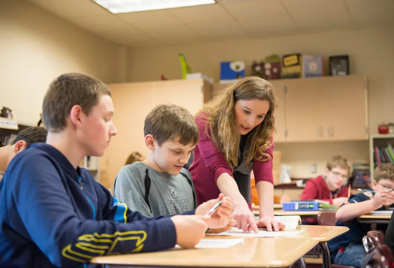 teacher helping students with a project in class