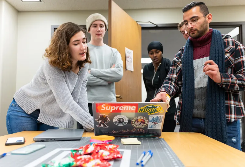 students discussing an assignment on a laptop