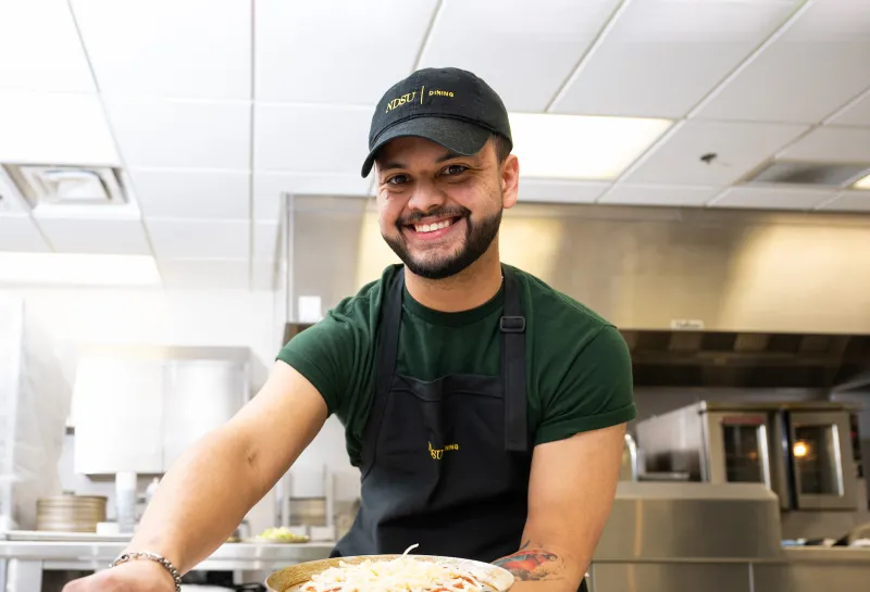student working in NDSU dining making pizza