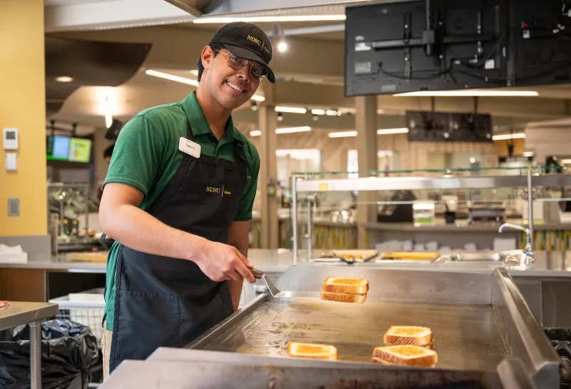 Student working in NDSU Dining making grilled cheese sandwiches
