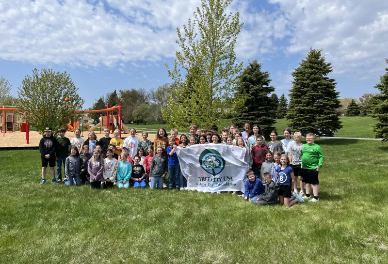 A group of kids hold up a flag smiling