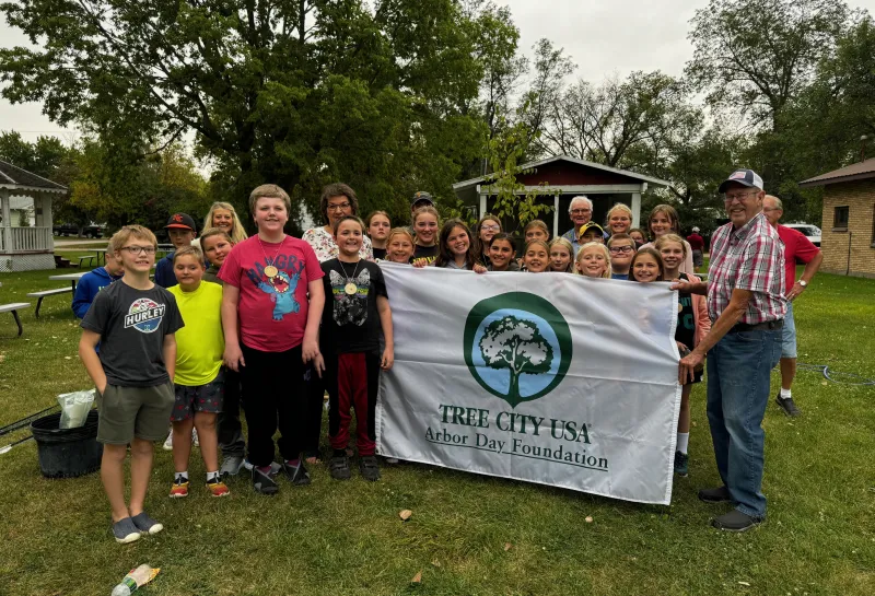 A group of kids hold up a flag smiling