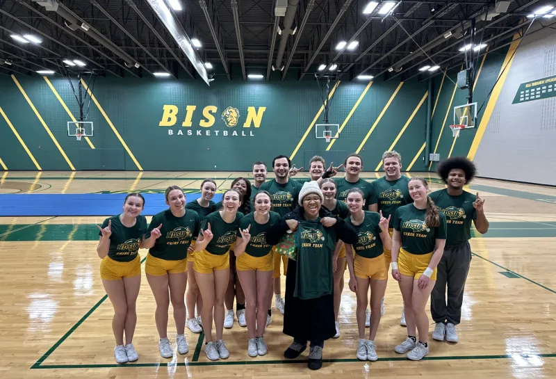 student standing with the cheer team