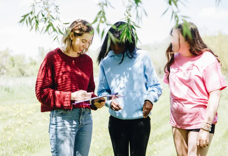 A young woman works on a worksheet with two younger girls
