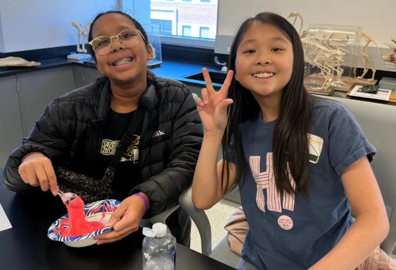two girls smiling while making slime at STEM event