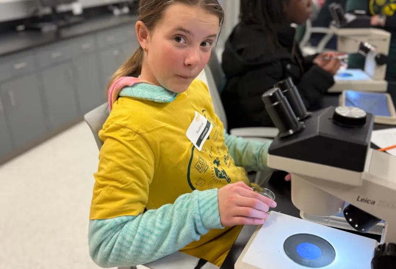 girls surprised by what she sees in microscope at STEM event