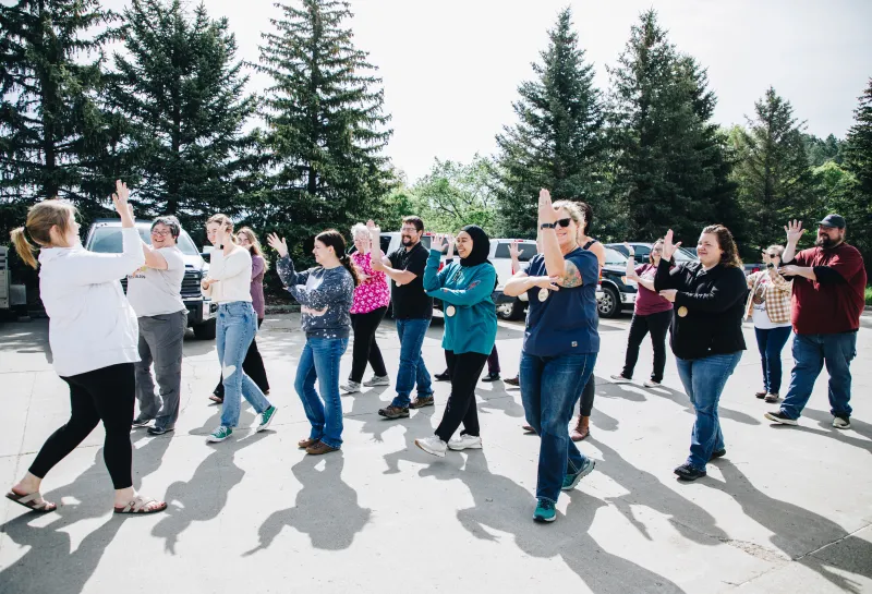 Educators hold their arm up as the sign for tree on a nature walk
