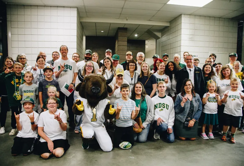 A group of people pose with a bison mascot