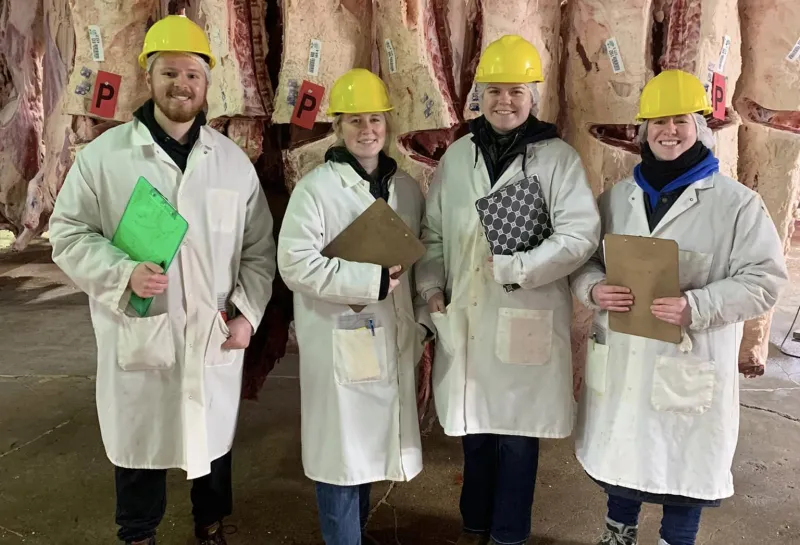 NDSU meats team posing with carcasses in background