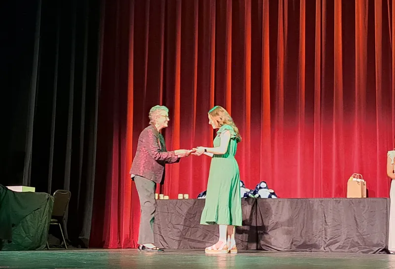 Student receiving an award on stage at the Spring 2024 SoDAA Sendoff.