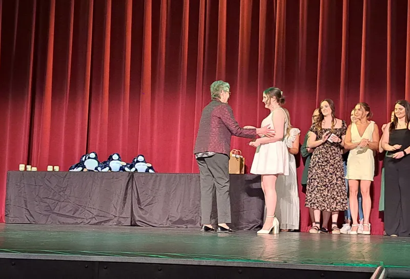 Student on stage with faculty at the Spring 2024 SoDAA Sendoff.