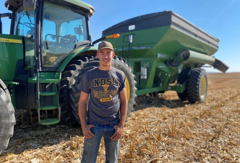 NDSU student stansing by tractor in field