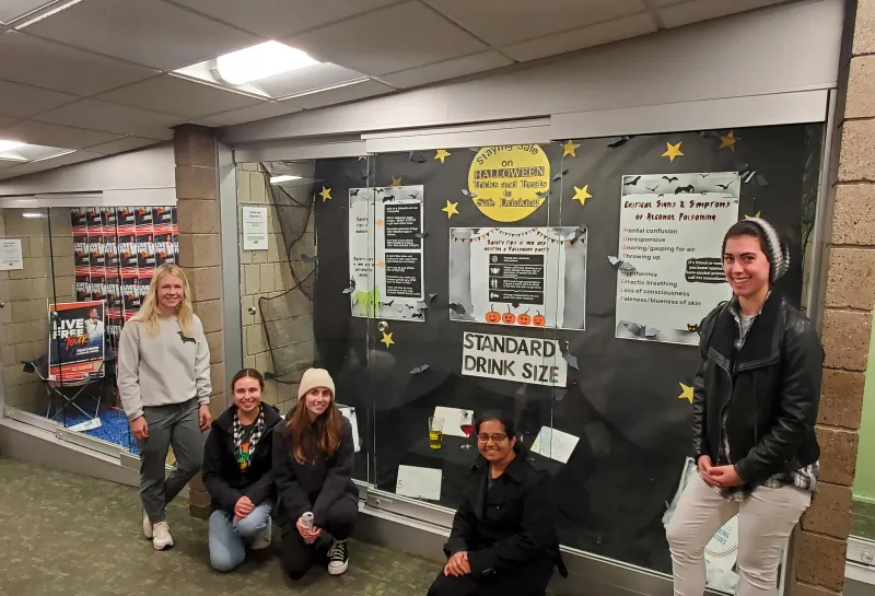 Peer Educators standing by Halloween Display Case
