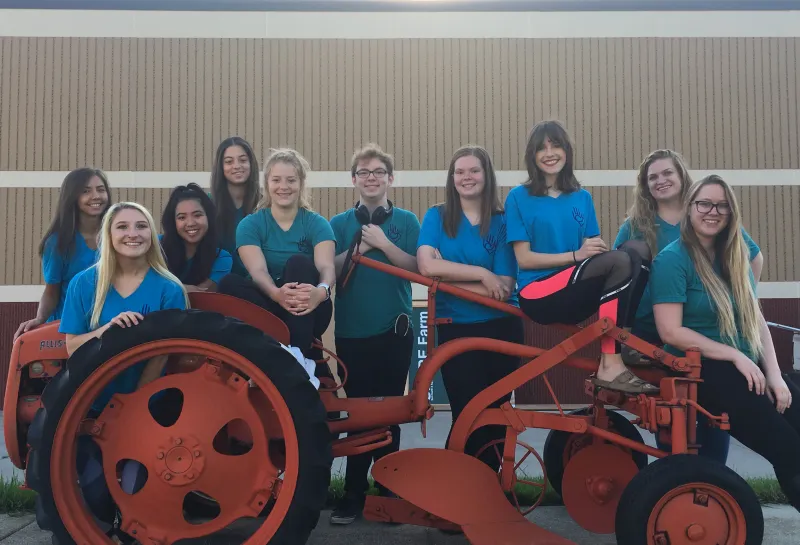 Students posing by tractor