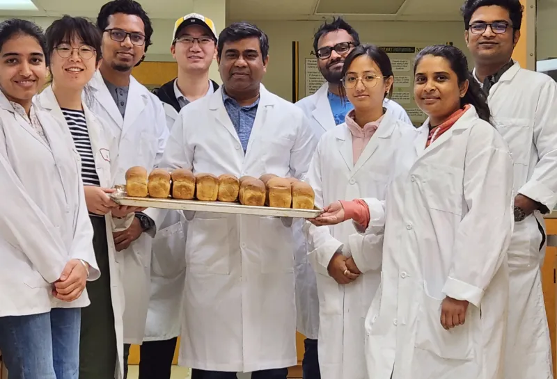 Dr. Shahidul Islam with his class students showing bread they vaked in the lab portion of class. 2023