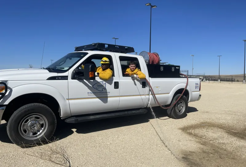 Wildland firefighters use a truck and hose to prepare to fight wildfires.