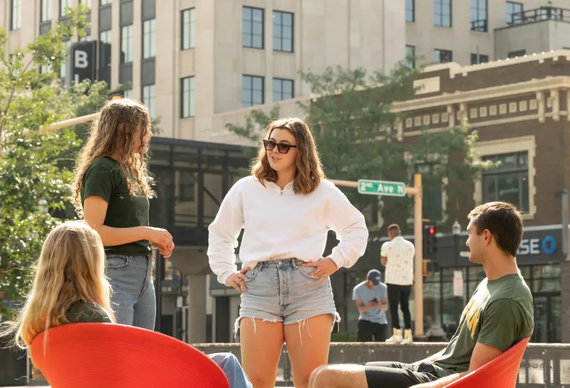 NDSU students sit in the red chairs at Broadway Square in downtown Fargo
