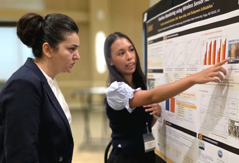 2026 summer REU students present their work at a poster session.