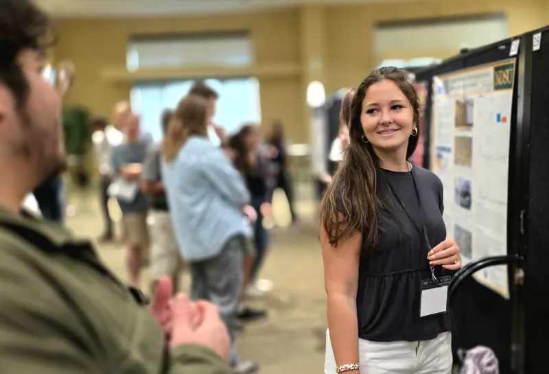 2026 summer REU students present their work at a poster session.