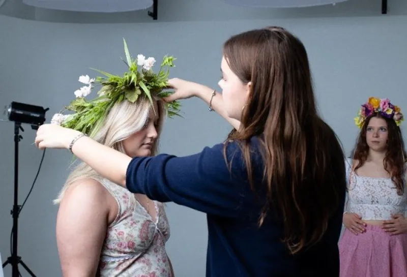 Student fixing a models flower crown.