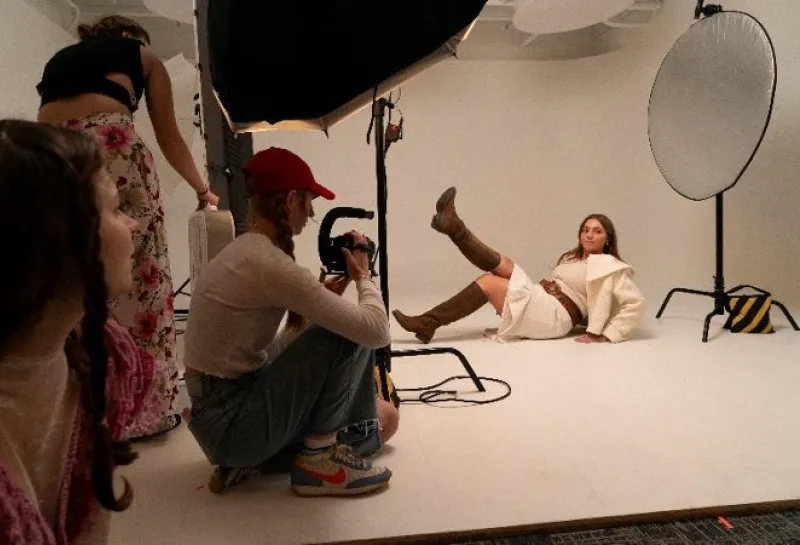 Model posing while photographer takes picture behind lights.