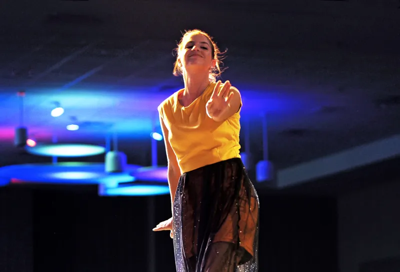 Model wearing a yellow and black dress while walking on runway.