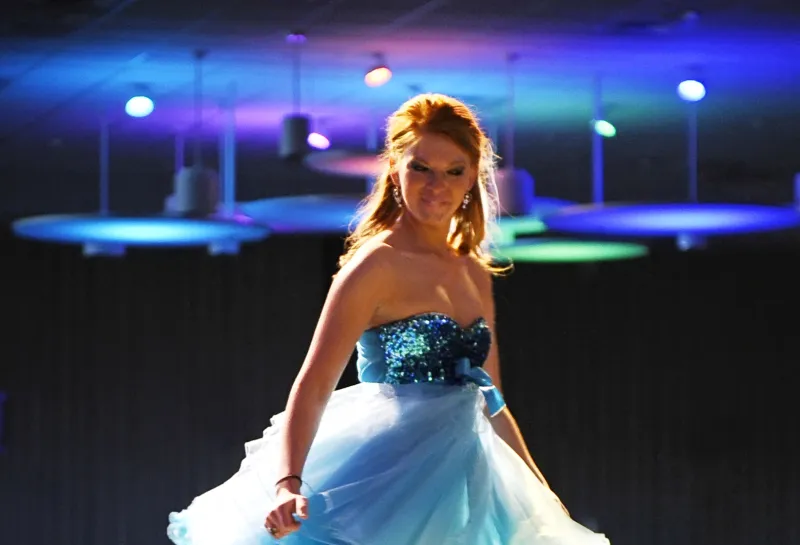 Model wearing a light blue dress while twirlling on runway.
