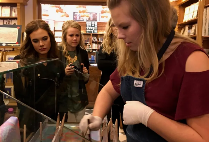 Student putting a paint brush into a paint pot.
