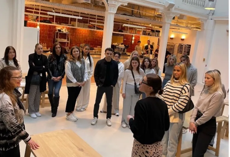 Students standing in foyer while listening to someone speak.